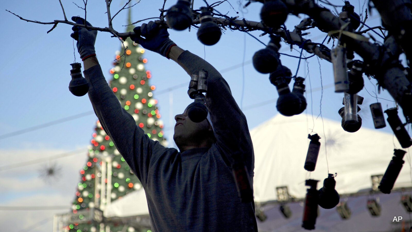 A Palestinian decorates a Christmas tree with tear gas canisters at Manger Square