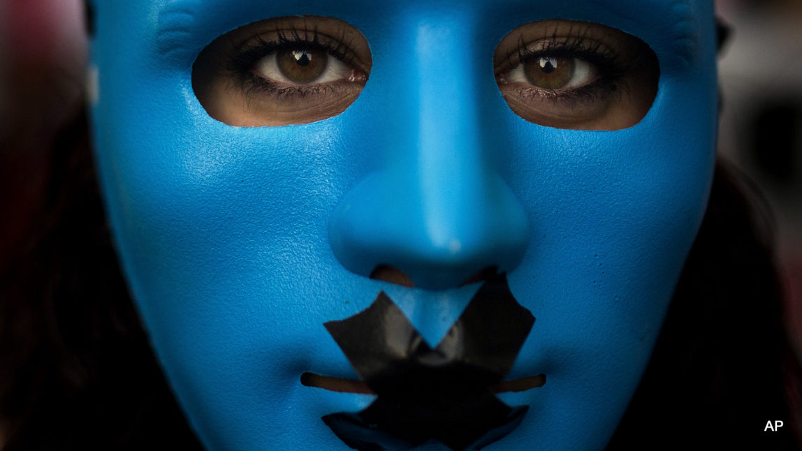 A protestor wears a mask with a gag as she marches against the Public Security Law in Madrid