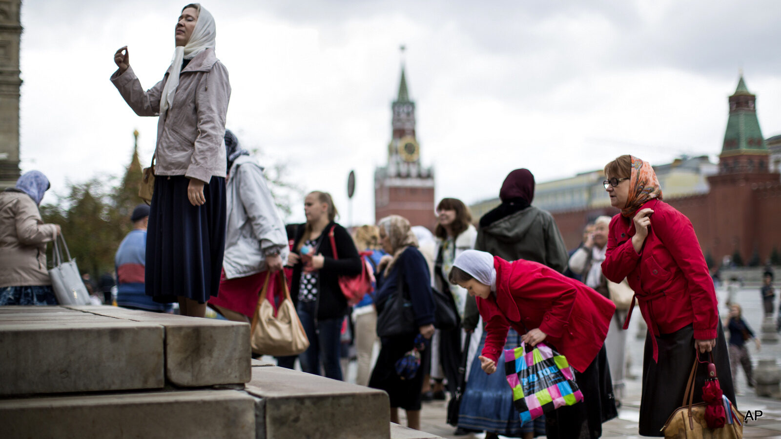 People cross themselves as they leave the Church of the Kazan Mother of God in Red Square after a religion service in honor of the Kazan Icon of the Mother of God in Moscow, Russia, Tuesday, July 21, 2015, with the Kremlin Wall and Spasskaya Tower are in the background. (