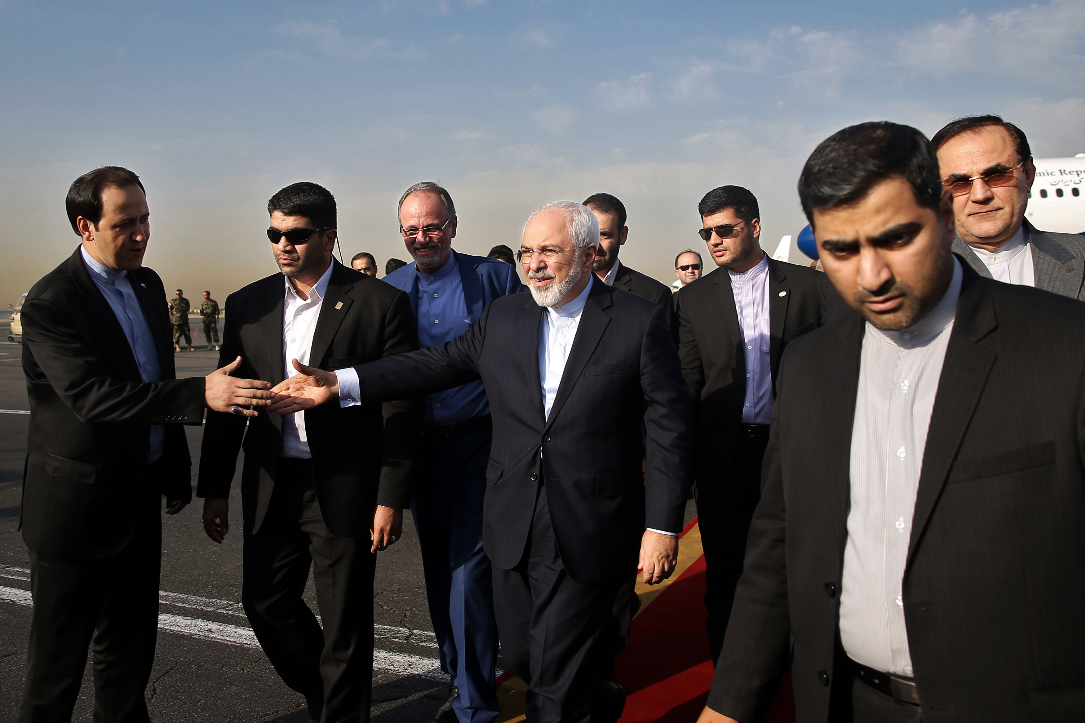 Iran's Foreign Minister Mohammad Javad Zarif, who is also Iran's top nuclear negotiator, center, shakes hands with an official upon arrival at the Mehrabad airport in Tehran, Iran, Wednesday, July 15, 2015. 