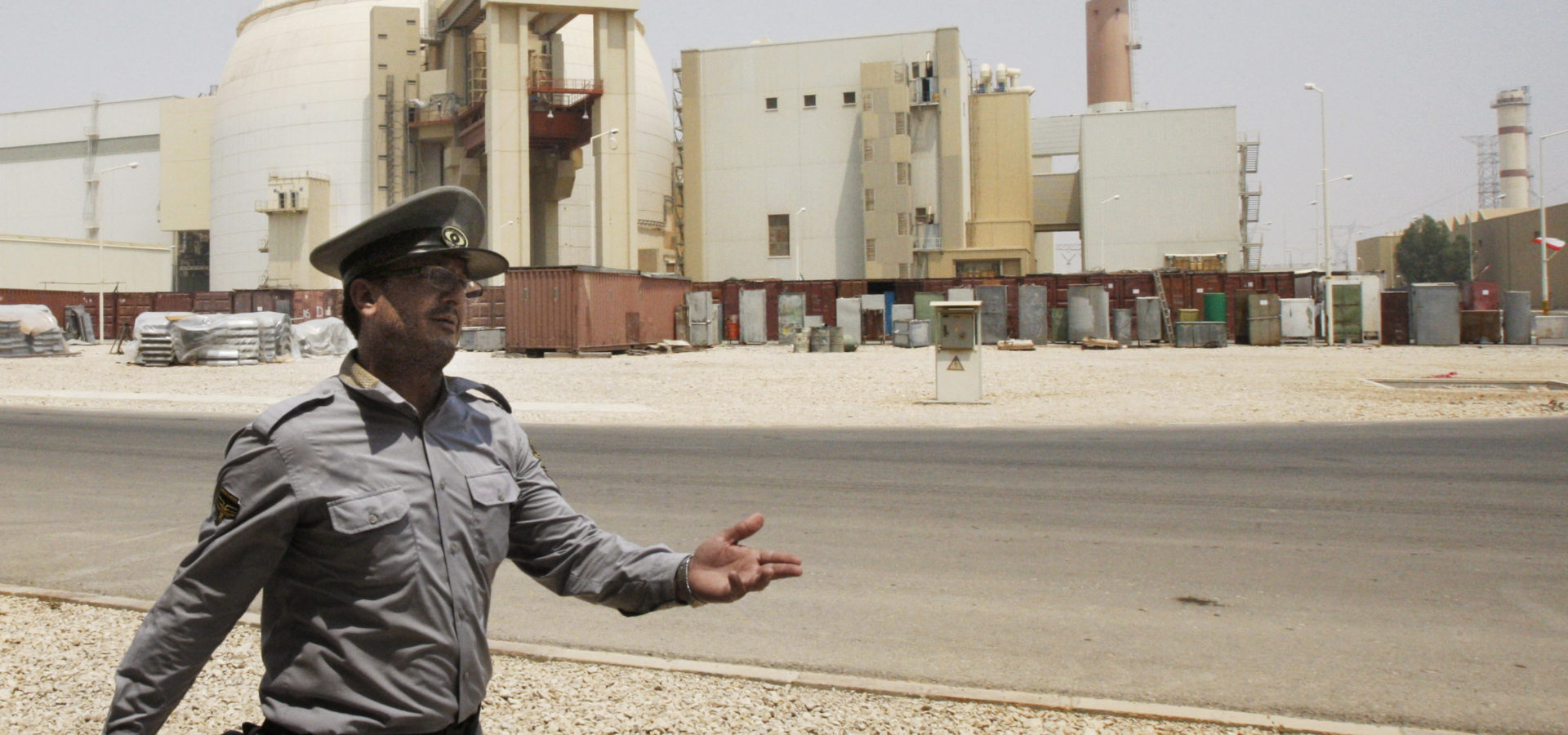An Iranian security officer directs media at the Bushehr nuclear power plant, with the reactor building seen in the background, just outside the southern city of Bushehr, Iran. (AP Photo/Vahid Salemi)