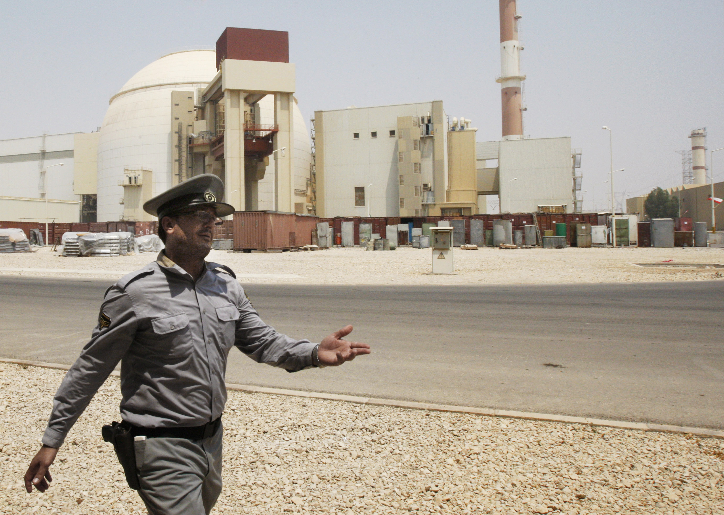 An Iranian security officer directs media at the Bushehr nuclear power plant, with the reactor building seen in the background, just outside the southern city of Bushehr, Iran.  (AP Photo/Vahid Salemi)