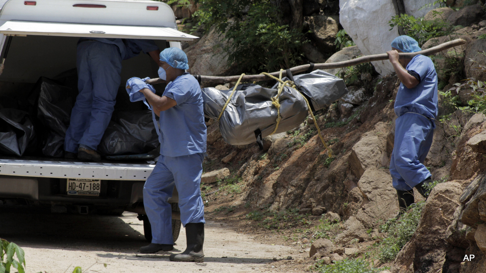 forensic workers load a body into a truck after at least 10 bodies were found in clandestine graves on the outskirts of the Pacific beach resort Acapulco, Mexico