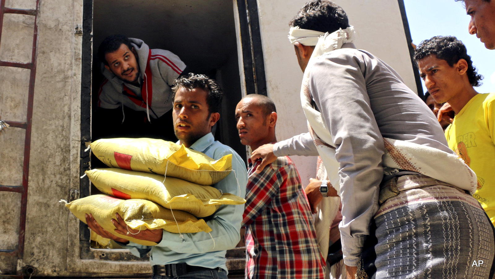 A Yemeni volunteer carries bags of rice to displaced people