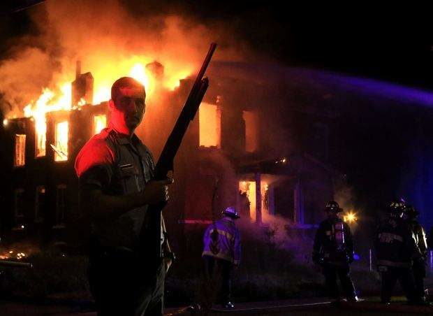 A St. Louis police officer stands guard as firefighters extinguish a fire in the 1300 block of Bayard Avenue on Wednesday, Aug. 19, 2015, after a fatal officer-involved shooting near Page Boulevard at Walton Avenue. Photo by Christian Gooden, cgooden@post-dispatch.com