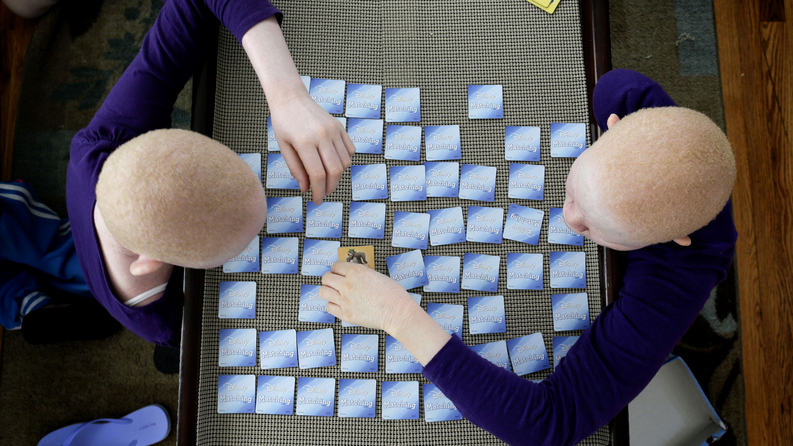Pendo Noni, left, and Kabula Masanja play a memory card game in New York on Tuesday, July 28, 2015. One out of every 1,400 citizens in Tanzania has albinism. Pendo and Kabula were attacked and dismembered in the belief that their body parts will bring wealth. (AP Photo/Julie Jacobson)