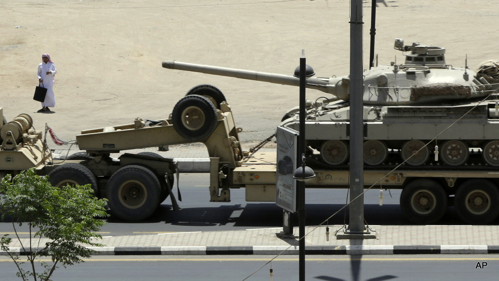 A Saudi man looks at an army tank being transported, in the city of Najran, Saudi Arabia, near the border with Yemen, Thursday, April 23, 2015. 