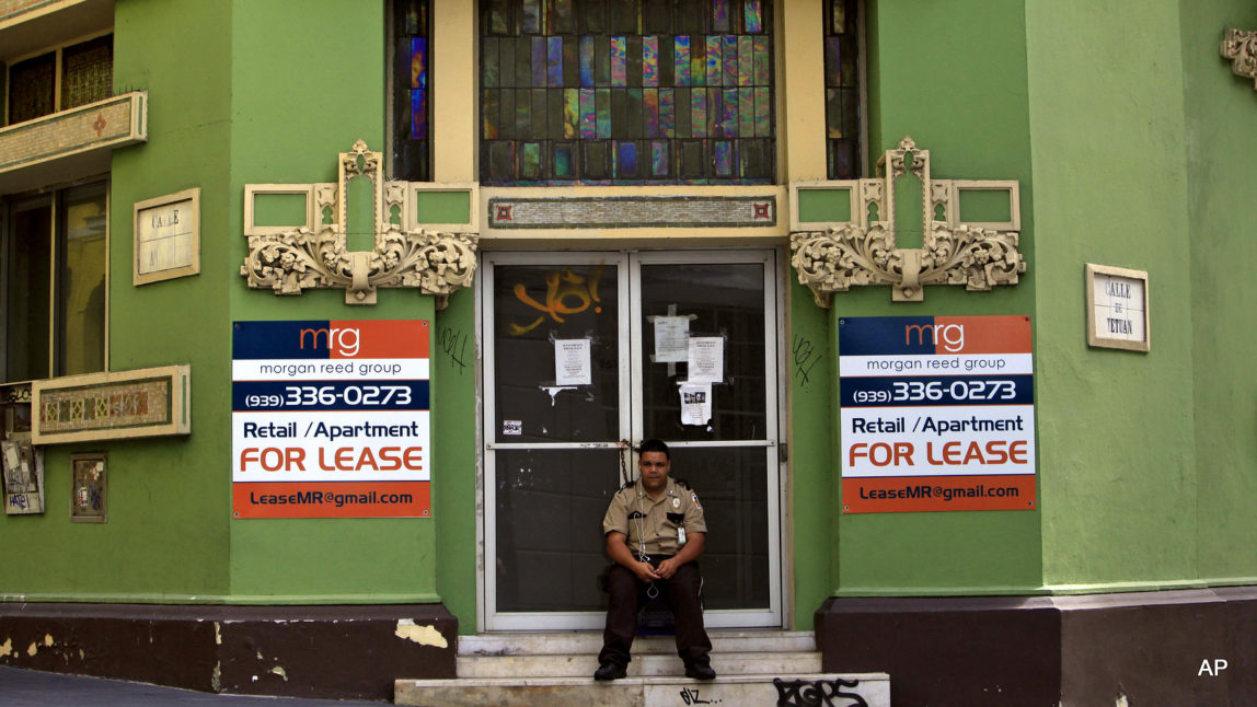 A private security guard sits in front of a closed down business in the colonial district of Old San Juan, Puerto Rico