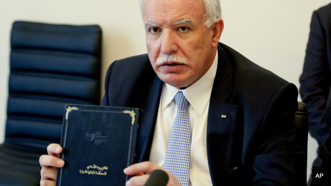 Palestinian Foreign Minister Riad Malki holds up a copy of the International Criminal Court's founding treaty, the Rome Statute