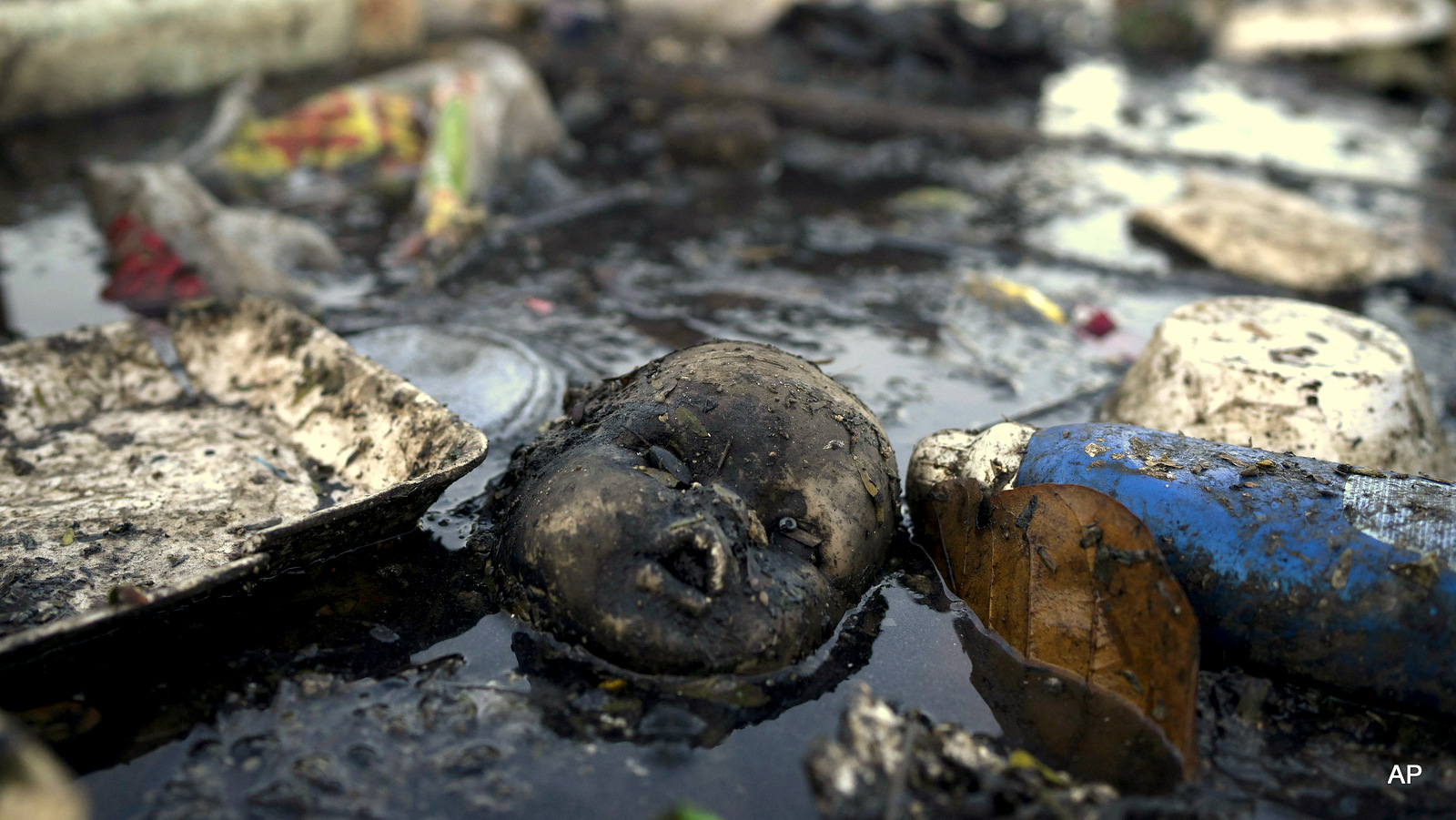 A doll's head floats in the polluted waters of a canal at the Mare slum complex in Rio de Janeiro, Brazil