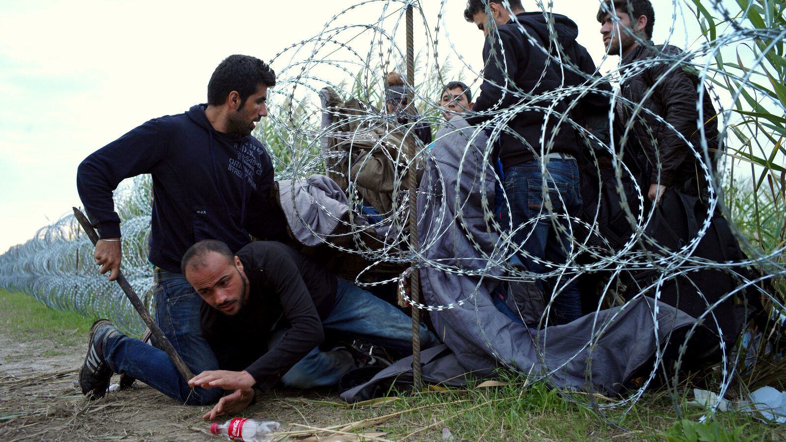 Syrian refugees cross into Hungary underneath the border fence on the Hungarian - Serbian border near Roszke, Hungary on Aug. 26, 2015. The number of refugees entering Hungary has reached a new high as the government hurries to build a 4-meter (13-foot) fence on the Serbian border to stop them. More than 140,000 migrants have reached Hungary on routes across the Balkans so far in 2015. Recently, some 80 percent of them are from war zones like Syria, Iraq and Afghanistan. (AP Photo/Bela Szandelszky)
