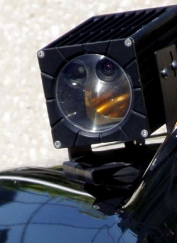 A camera mounted on the trunk of a police car scans traffic on the streets, aggregating data such as patterns on travel and frequency of visits to a certain area.