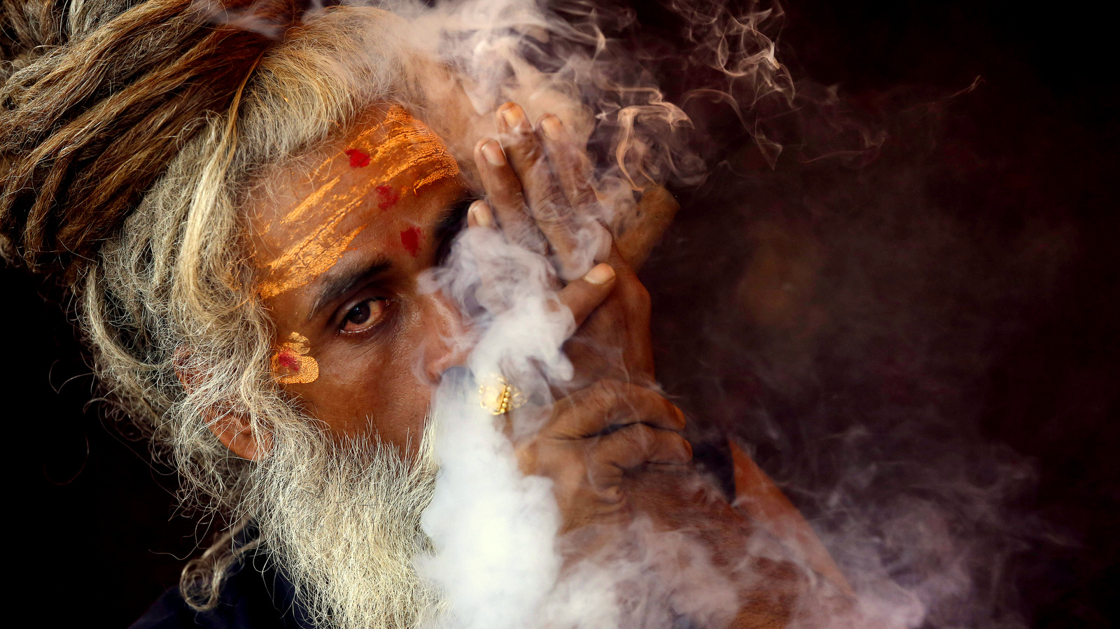 A Naga sadhu, or naked Hindu holy man, smokes hashish inside his tent during Kumbh Mela, or Pitcher festival, at Trimbakeshwar, India, Friday, Aug. 28, 2015. Hindus believe taking a dip in the waters of a holy river during the festival will cleanse them of their sins. The festival is held four times every 12 years. (AP Photo/Rajanish Kakade)