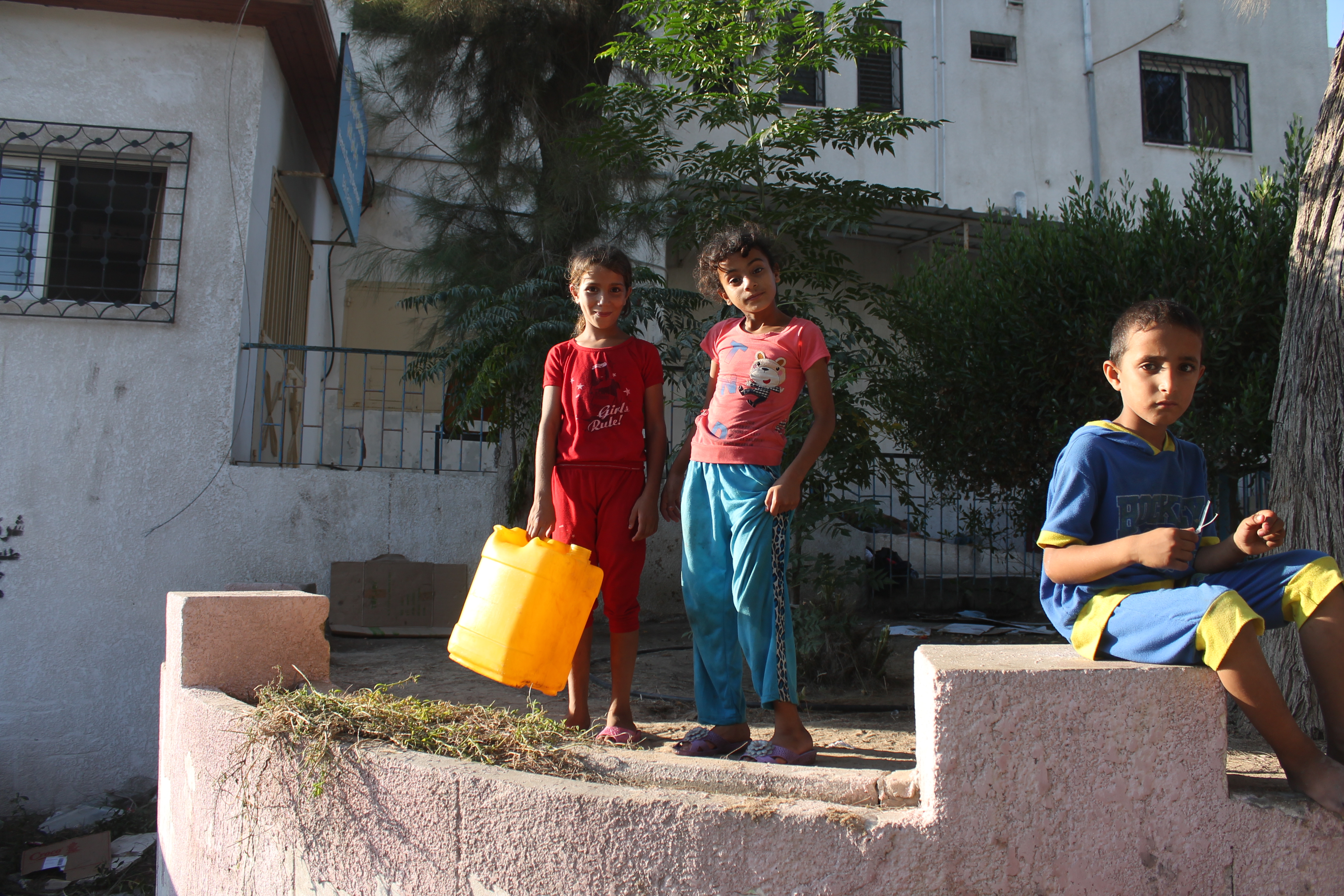 Los palestinos desplazados por los ataques israelíes esperan obtener agua de tanques portátiles cerca de un campamento improvisado detrás del hospital al-Shifa de Gaza, el sábado 26 de julio de 2014. (Joe Catron)