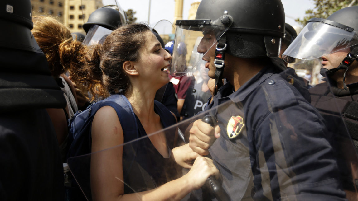 A Lebanese anti-government protester faces off with a riot policeman on a road leading to the parliament building before a scheduled meeting of political leaders to try to solve the on-going trash crisis and government dysfunction, in downtown Beirut, Lebanon, Wednesday, Sept. 16, 2015. (AP Photo/Hassan Ammar)