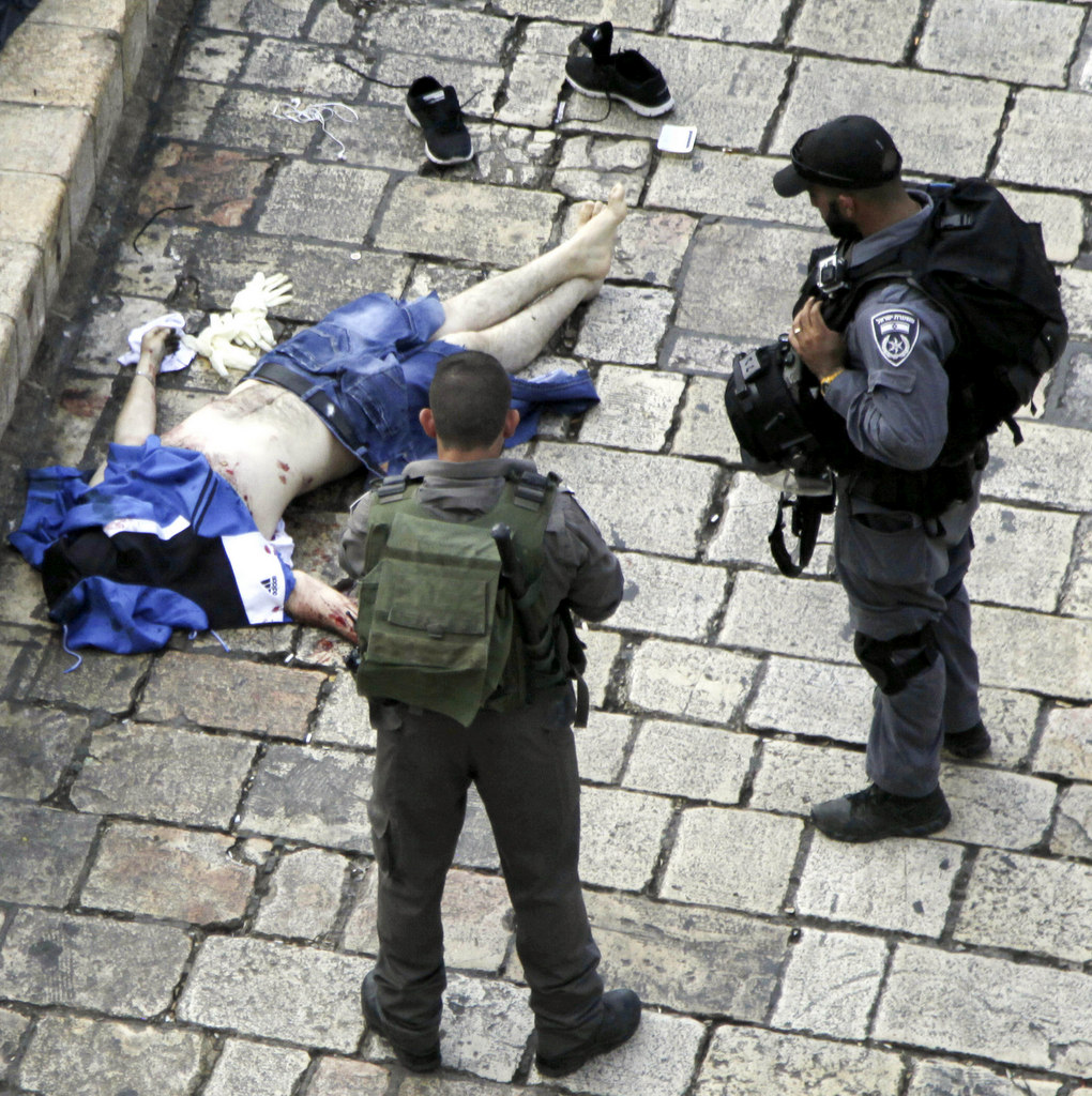 Israeli police stand near the body of a Palestinian who, according to the police, stabbed two police officers, then other police forces opened fire and killed him, but also wounded one of their own, at the Damascus Gate of Jerusalem's Old City, Saturday, Oct. 10, 2015. Palestinians carried out two stabbing attacks in Jerusalem on Saturday before being shot dead by police, while another two Palestinians were killed during a violent demonstration near the Gaza border fence. The violence, including the first apparent revenge attack by an Israeli Friday and increasing protests by Israel's own Arab minority, has raised fears of the unrest spiraling further out of control. (AP Photo/Mahmoud Illean)