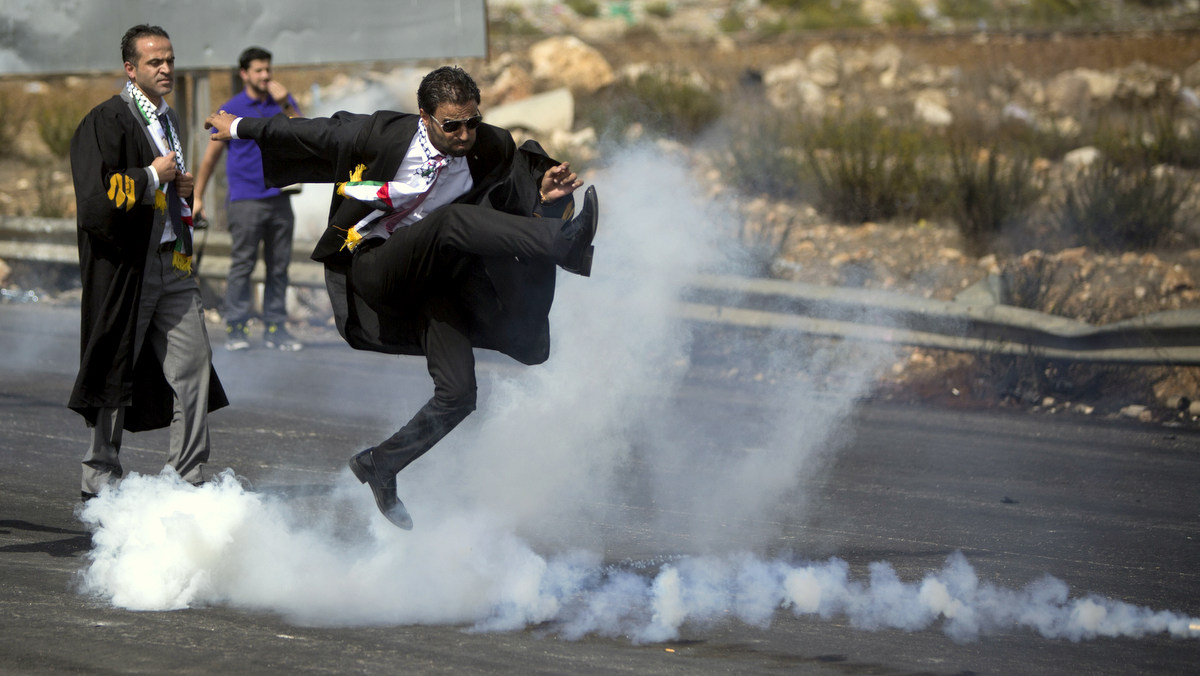 A lawyer wearing his official robes kicks a tear gas canister back toward Israeli soldiers during a demonstration by scores of Palestinian lawyers called for by the Palestinian Bar Association in solidarity with protesters at the Al-Aqsa mosque compound in Jerusalem's Old City, near Ramallah, West Bank, Monday, Oct. 12, 2015. In recent weeks, at least 25 Palestinians, including nine attackers, have been killed by Israeli forces, while five Israelis have been killed in attacks. (AP Photo/Majdi Mohammed)