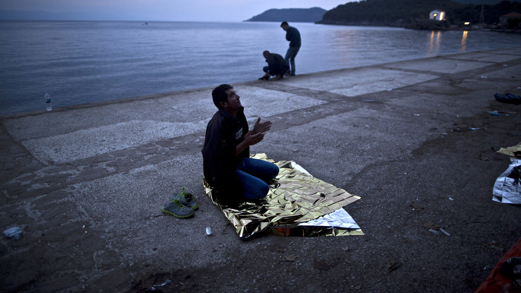 An Afghan refugee offers early morning prayers on a roadside as he and others spent the night at a resting point after arriving on a dinghy from the Turkish coast to the northeastern Greek island of Lesbos, Tuesday, Oct. 6 , 2015. (AP Photo/Muhammed Muheisen)