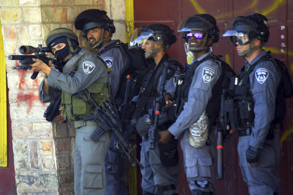 An Israeli policeman aims, during clashes with Palestinian demonstrators, in Shuafat refugee camp in Jerusalem, Friday, Oct. 9, 2015.