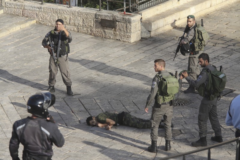 Israeli police stand around a Palestinian shot after he allegedly tried to stab a person at Damascus Gate of the Jerusalem's Old City, Wednesday, Oct. 14, 2015, Israeli police said. (AP Photo/Oren Ziv)