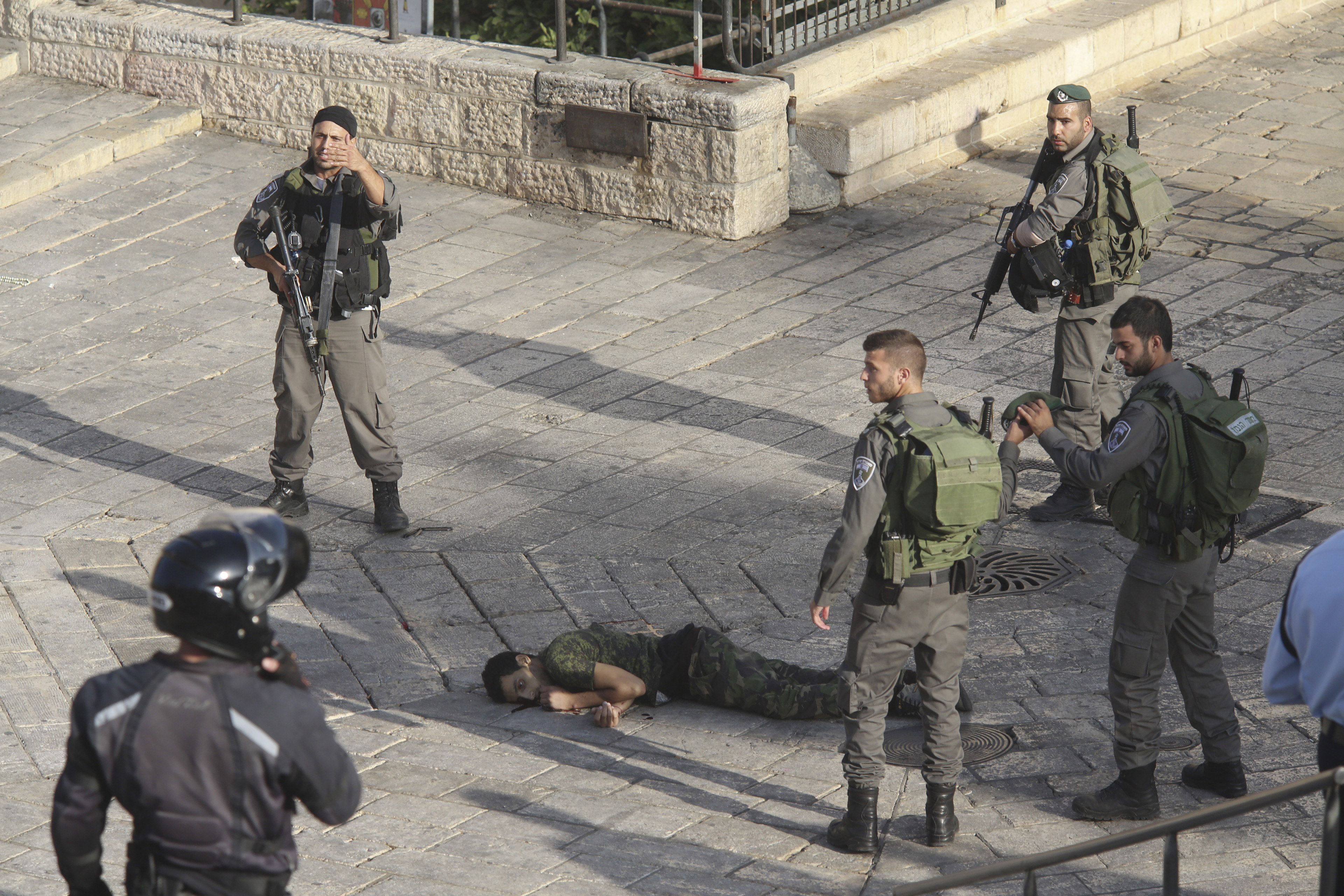 Israeli police stand around a Palestinian shot after he allegedly tried to stab a person at Damascus Gate of the Jerusalem's Old City, Wednesday, Oct. 14, 2015, Israeli police said. (AP Photo/Oren Ziv)