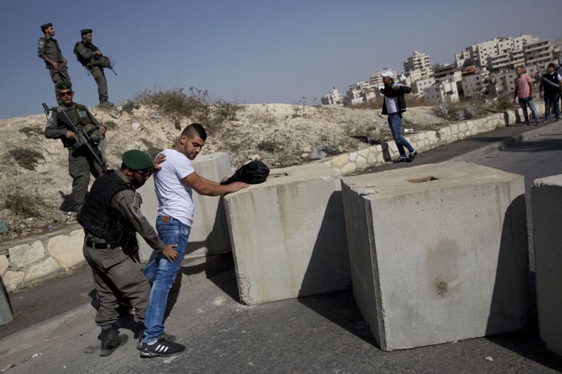 Israeli border police search a Palestinian, next to newly placed concrete blocks in an east Jerusalem neighborhood, Thursday, Oct. 15, 2015. Israel erected checkpoints and deployed several hundred soldiers in the Palestinian areas of the city Wednesday as it stepped up security following a series of attacks in Jerusalem. (AP Photo/Oded Balilty)