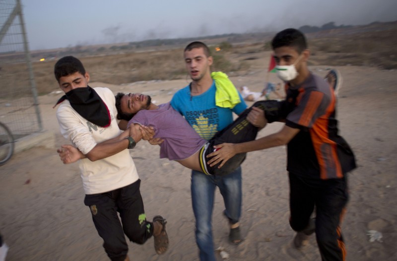Palestinian protesters evacuate a wounded man during clashes with Israeli soldiers by the Israeli border with Gaza in Buriej, central Gaza Strip, Thursday, Oct. 15, 2015. (AP Photo/ Khalil Hamra)