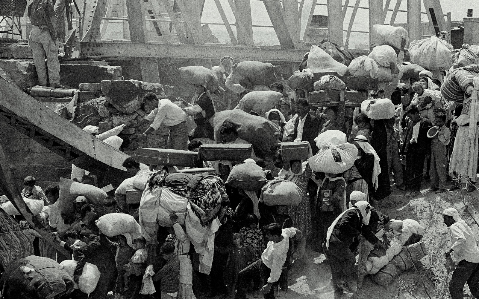 Palestinian refugees carry their belongings as they prepare to cross the wrecked Allenby Bridge over the Jordan River from the Israeli-occupied section of Jordan, June 22, 1967. Many of the refugees said they were forced to leave by the Israelis. (AP Photo/Bernard Frye)