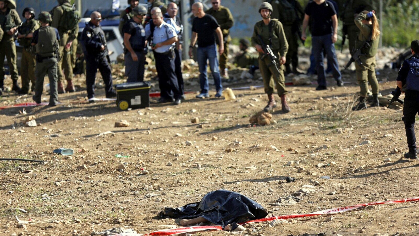 Israeli soldiers stand near the body of 27-year-old Palestinian Fadi Froukh, in the Beit Einun junction east of the West Bank city of Hebron, Sunday, Nov 1, 2015. (AP/Nasser Shiyoukhi)