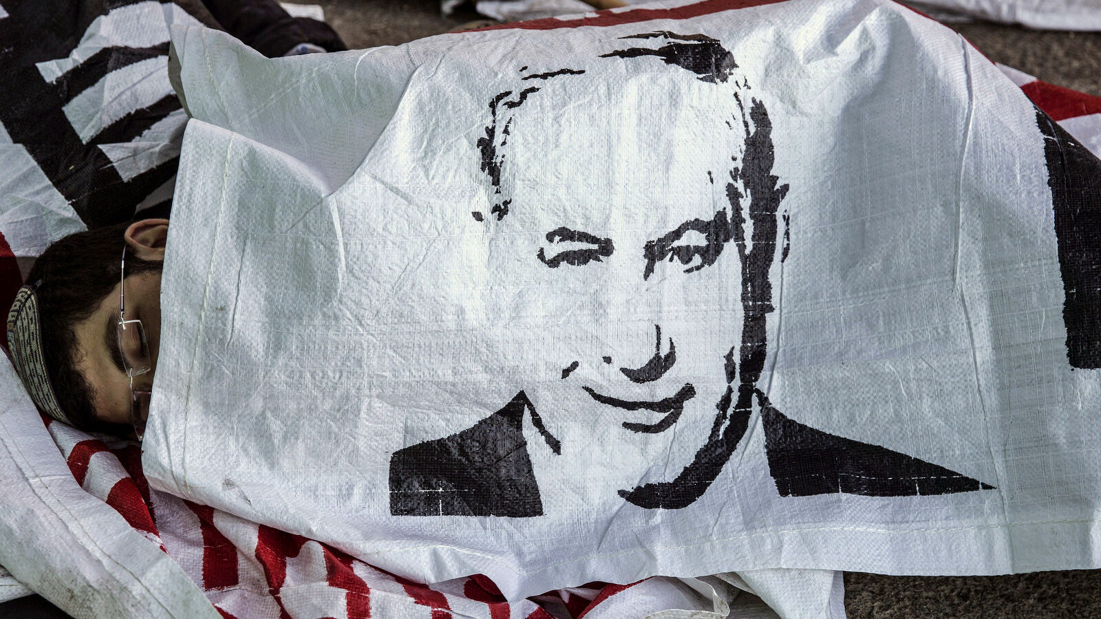 An Israeli settler sleeps under a banner of Israeli Prime Minister Benjamin Netanyahu, in the Jewish settlement of Beit El after a night stand off with police, near the West Bank town of Ramallah, Wednesday, July 29, 2015. The Israeli Prime Minister's office said Wednesday it has approved the "immediate construction" of 300 housing units in the West Bank settlement of Beit El. The announcement came amid a standoff, where Israeli settlers clashed with Israeli forces as authorities began to dismantle the contested West Bank settlement housing complex after Israel's Supreme Court ruled Wednesday that it must be demolished. (AP Photo/Tsafrir Abayov)