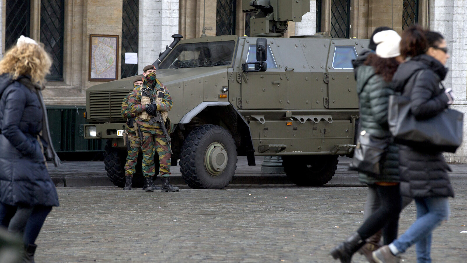 People walk as Belgian Army soldiers patrol in the historic Grand Place in the center of Brussels on Monday, Nov. 23, 2015. The Belgian capital Brussels has entered its third day of lockdown, with schools and underground transport shut and more than 1,000 security personnel deployed across the country. (AP Photo/Virginia Mayo)