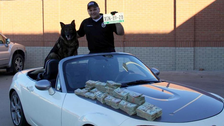 A police officer proudly displays his bounty taken from a police seizure.