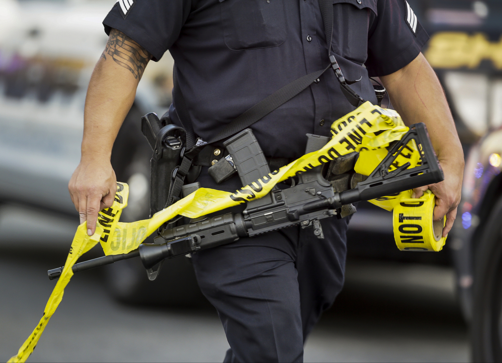 A police officer deploys tape to an area near where attackers opened fire on a banquet at a social services center for the disabled in San Bernardino. (AP Photo/Damian Dovarganes)