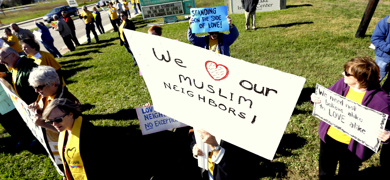 Paula Criswell, center, holds a sign as she joins others in a rally to show support for Muslim members of the community near the Clear Lake Islamic Center in Webster, Texas on Friday, Dec. 4, 2015. Members of several churches showed their support as attendees made their way to the center for Friday prayers. (AP Photo/David J. Phillip)