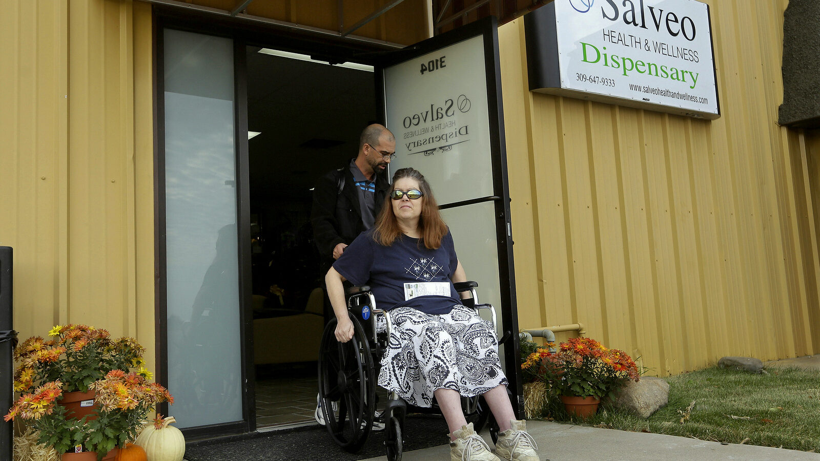 Shamay Flaharty, of Lewiston, Ill., who has multiple sclerosis and is hoping cannabis will help ease her pain and headaches, leaves with Eric Sweatt, partner and manager of Salveo Health and Wellness. (AP Photo/Seth Perlman)