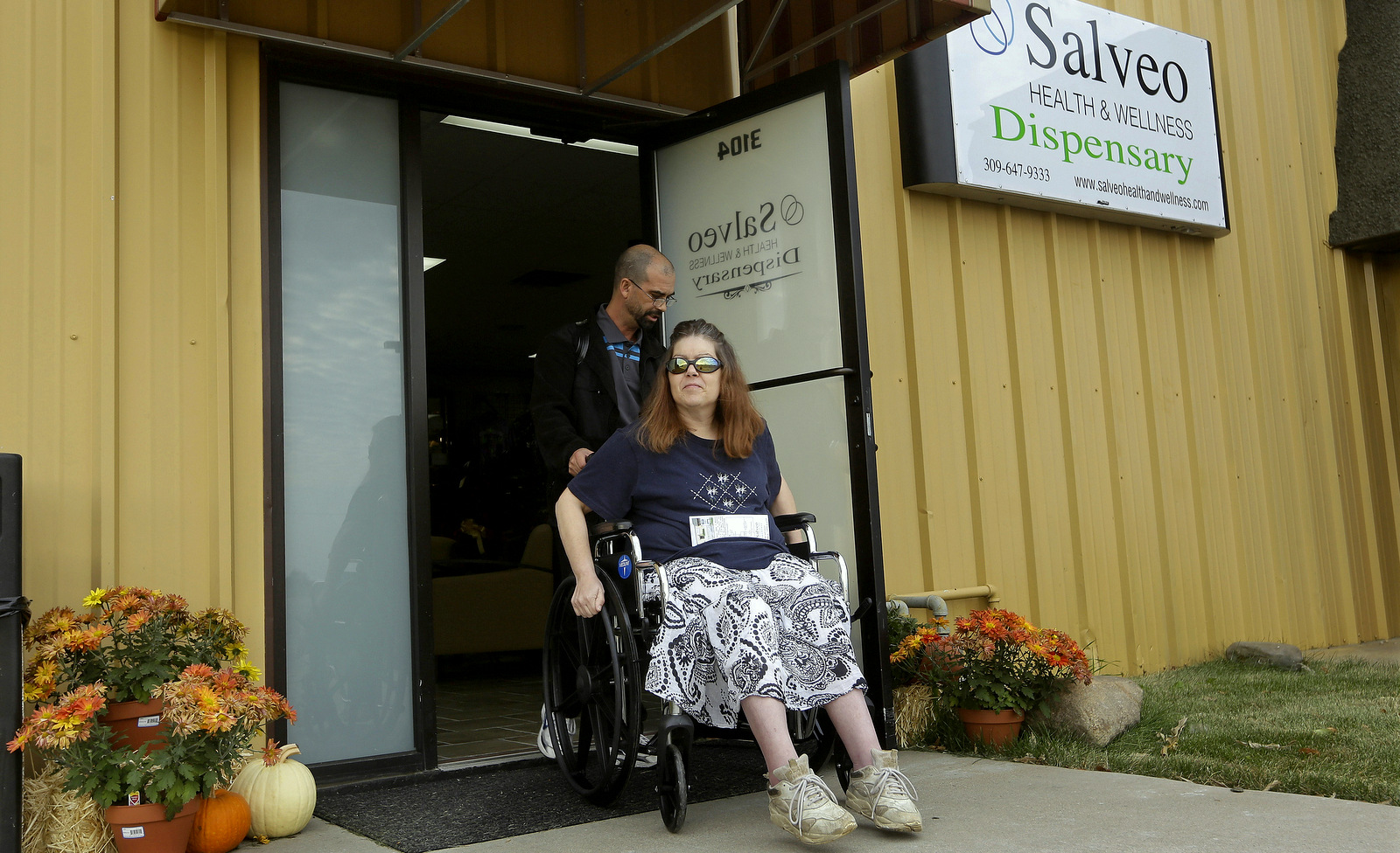 Shamay Flaharty, of Lewiston, Ill., who has multiple sclerosis and is hoping cannabis will help ease her pain and headaches, leaves with Eric Sweatt, partner and manager of Salveo Health and Wellness. (AP Photo/Seth Perlman)