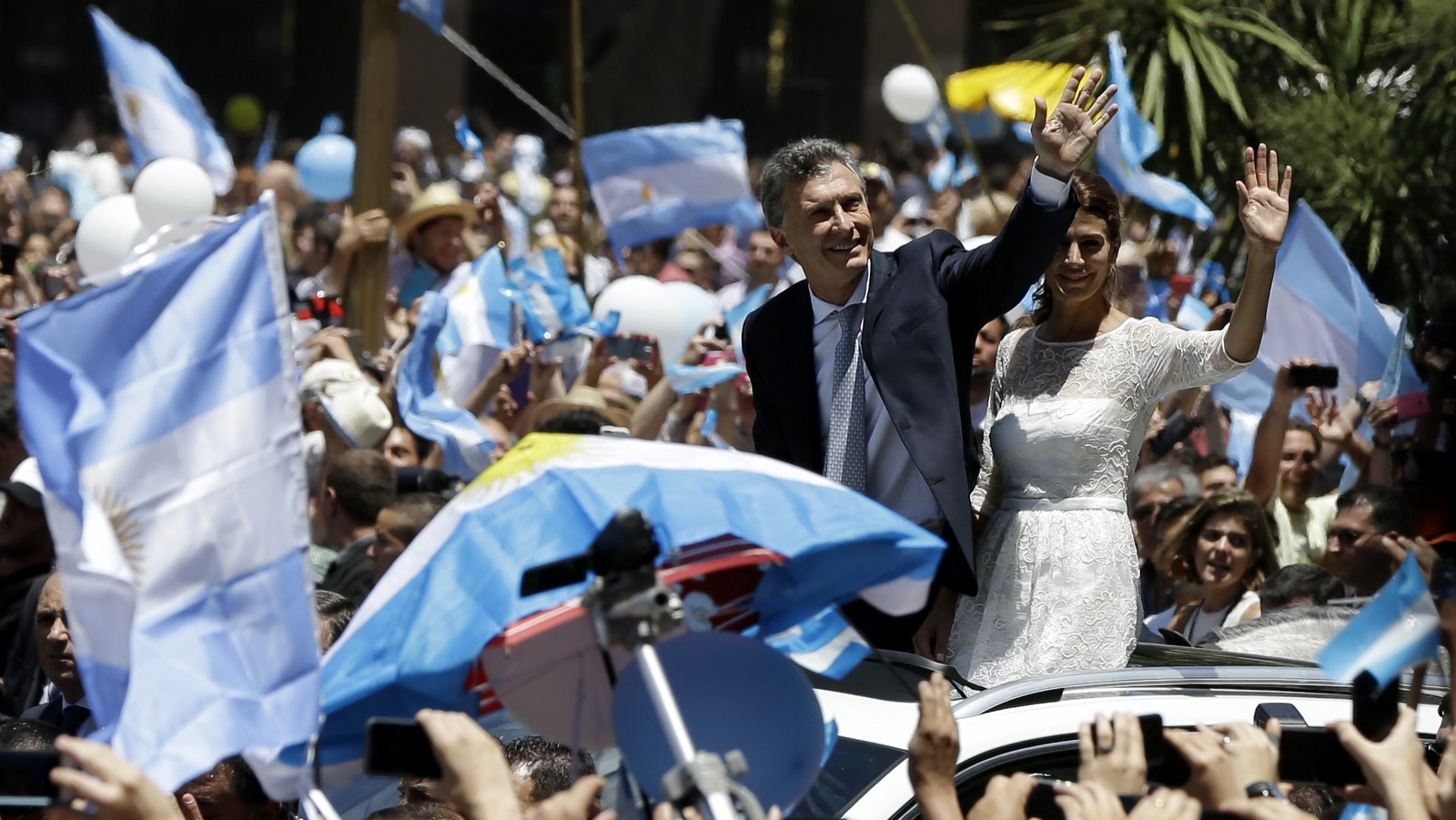 Mauricio Macri and first lady Juliana Awada wave to the crowd as they drive through the Plaza de Mayo square on their way to the presidential palace after he was sworn in as Argentina's new president in Buenos Aires, Argentina, Thursday, Dec. 10, 2015. Macri assumed power Thursday replacing President Cristina Fernandez.(AP Photo/Ricardo Mazalan)
