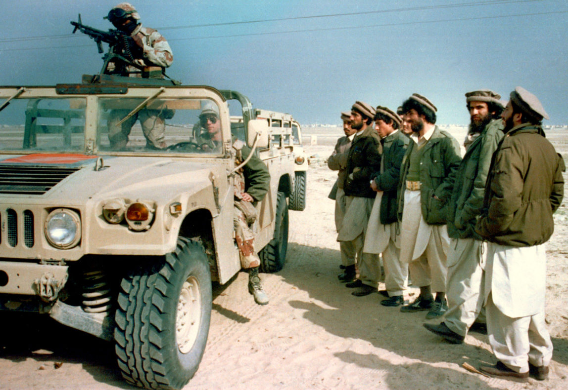 A group of Afghan mujahedeens, Islamic guerrillas, look over a U.S. Marine humvee in eastern Saudi Arabia, Monday, Feb. 11, 1991. The Marines visited a camp consisting of about 300 mujahedeens who have been asked by the Saudi government to help fight against Iraq in the Gulf War. (AP Photo/Department of Defense)