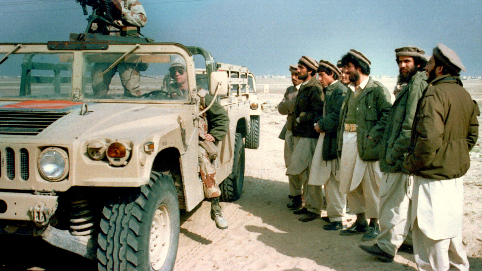 A group of Afghan mujahedeens, Islamic guerrillas, look over a U.S. Marine humvee in eastern Saudi Arabia, Monday, Feb. 11, 1991. The Marines visited a camp consisting of about 300 mujahedeens who have been asked by the Saudi government to help fight against Iraq in the Gulf War. (AP Photo/Department of Defense)