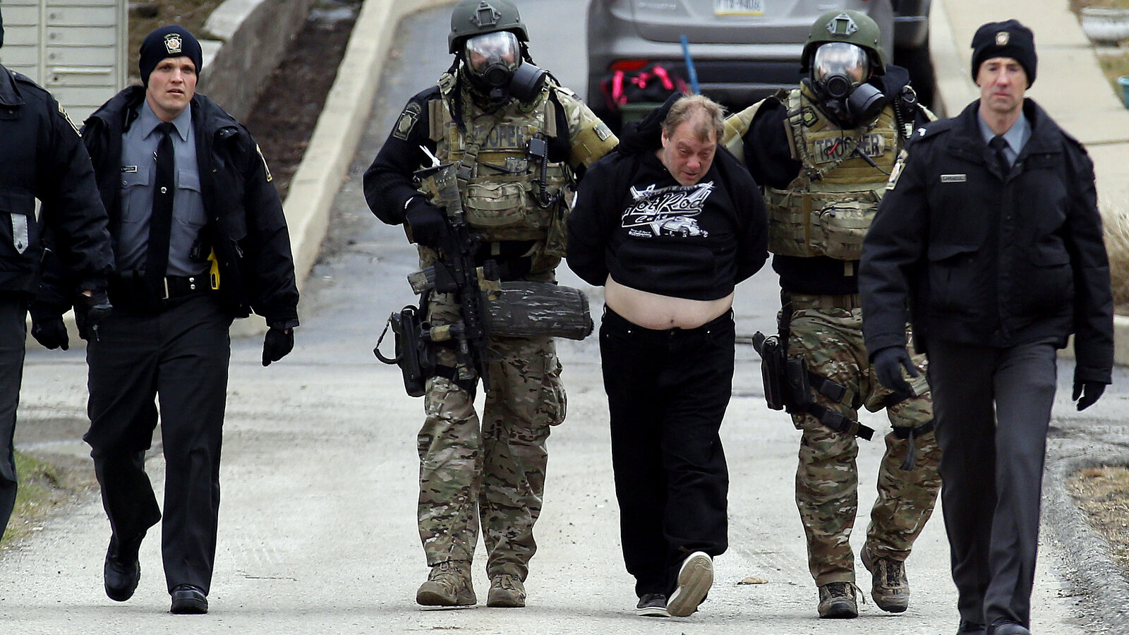 Police escort a suspected fugitive wanted in connection with a bomb threat after a tense eight hour standoff in Hempfield, Pa. The recent Planned Parenthood shooting in Co. resulted in police taking the conservative white male suspect alive causing many to question if race plays a role in who survives police staondoffs. (AP Photo/Keith Srakocic)