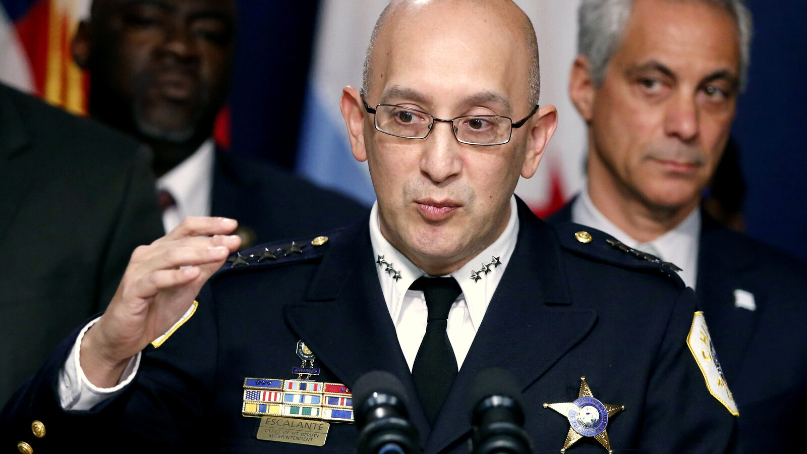 Chicago Police Superintendent John Escalante, left, speaks as Mayor Rahm Emanuel, right, listens, during a news conference in Chicago. As it scrambles to regain public trust shattered by the video of a black 17-year-old being shot 16 times by a white officer, the Chicago Police Department released crime statistics Friday, Jan. 1, 2016, that reveal a drop in some major crimes in the city but a significant increase in the number of homicides and shootings. Dec. 30, 2015. (AP Photo/Charles Rex Arbogast)