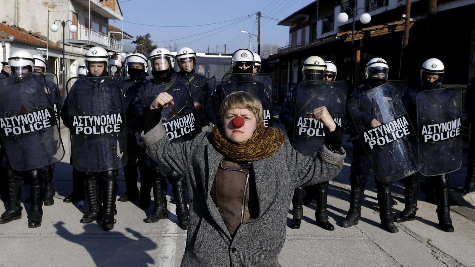 A protester with a red nose poses in front of a police cordon at the Greek-Turkish border at the Greek village of Kastanies on Sunday, Jan. 24, 2016. Police blocked the protesters from reaching the border post. The demonstrators held two days of rallies in the border area to demand that the government ease border transit restrictions after dozens more refugees and migrants drowned this week which crossing from Turkey to the Greek islands. (AP Photo/Thanassis Stavrakis)