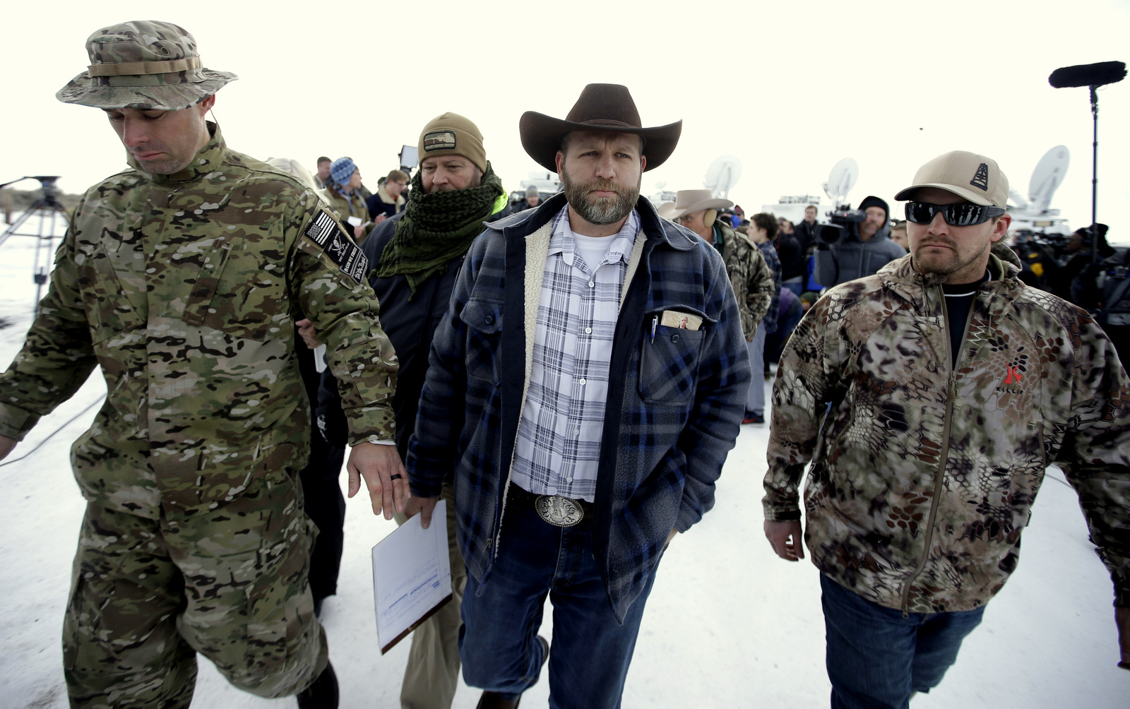 Ammon Bundy, center, one of the sons of Nevada rancher Cliven Bundy, walks off after speaking with reporters during a news conference at Malheur National Wildlife Refuge headquarters Monday, Jan. 4, 2016, near Burns, Ore. Bundy, who was involved in a 2014 standoff with the government over grazing rights told reporters on Monday that two local ranchers who face long prison sentences for setting fire to land have been treated unfairly. (AP Photo/Rick Bowmer)