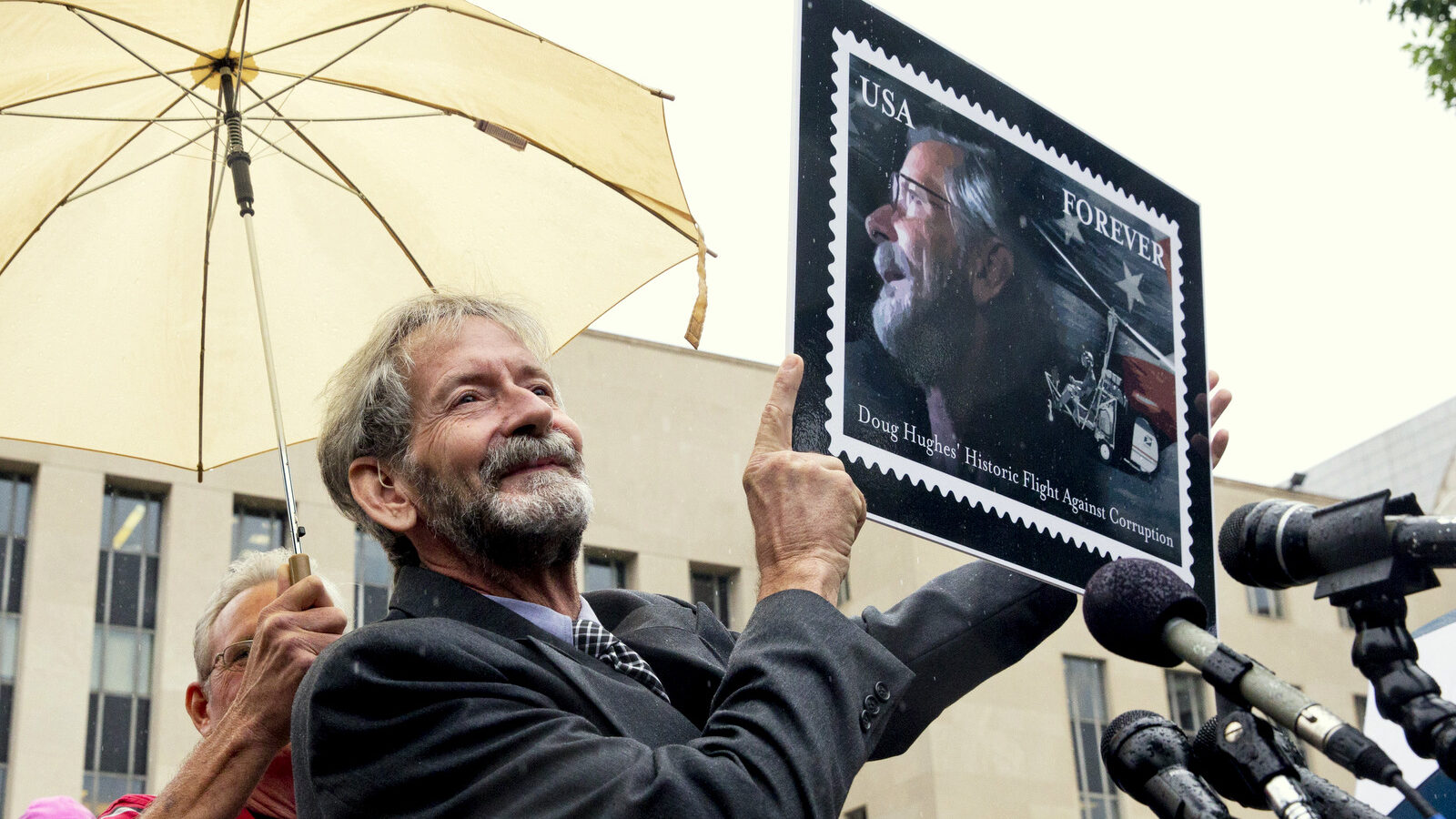Douglas Hughes of Florida holds up a design for a stamp that was given to him by an artist as a gift, while meeting with reporters outside federal court in Washington, Thursday, May 21, 2015, . Hughes, who flew a gyrocopter through some of America's most restricted airspace before landing at the Capitol pleaded not guilty on Thursday to the six charges he faces. (AP Photo/Jacquelyn Martin)