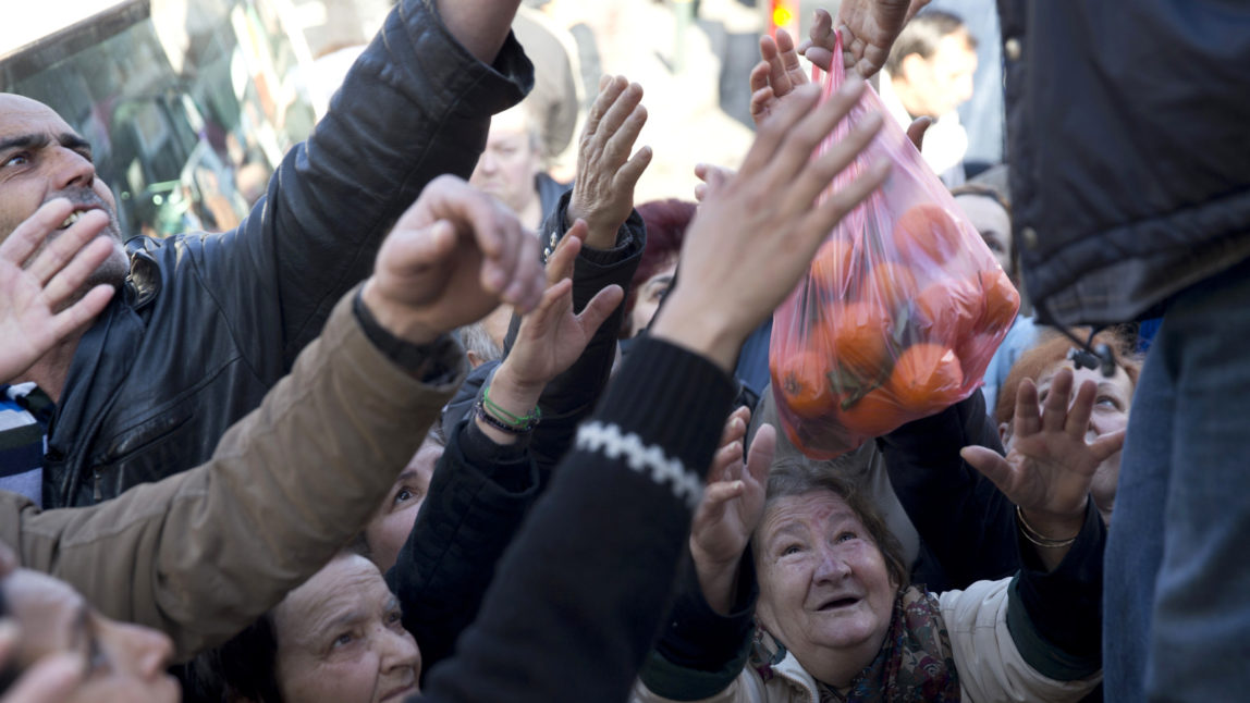 Bystanders wait to be handed bags of oranges during a free distribution of fruit and vegetables as a protest by farmers and vendors over proposed pension reforms, in Athens on Wednesday, Jan. 27, 2016. Greece's leftwing government is facing an escalating wave of protests over its proposed pension overhaul that has been demanded by bailout creditors. (AP Photo/Petros Giannakouris)