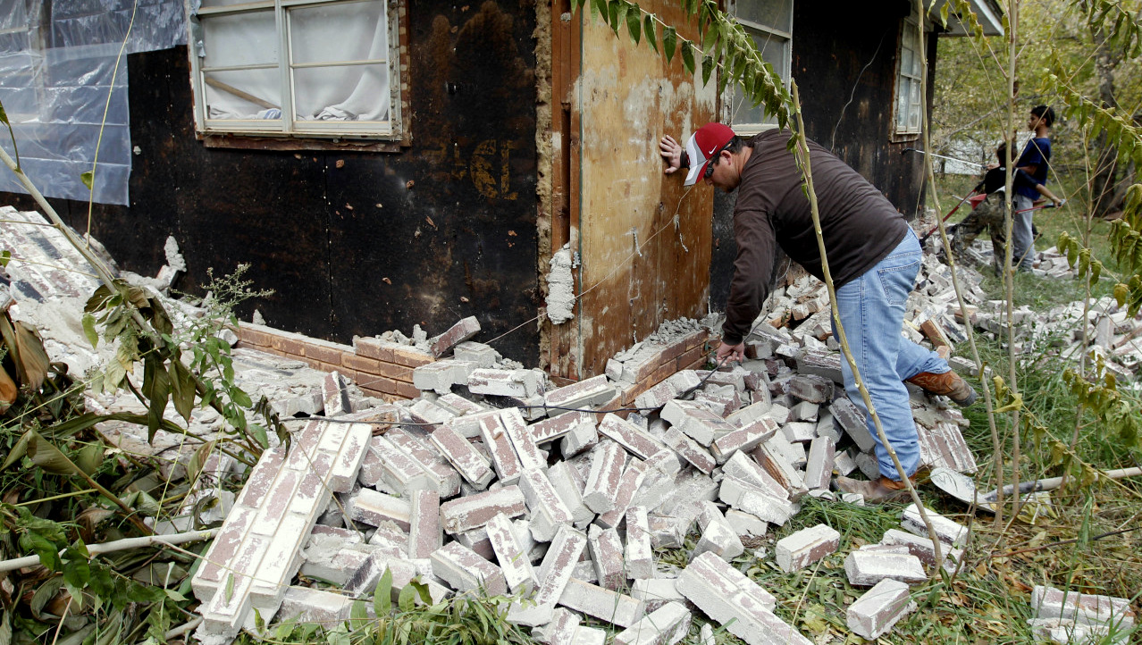 Chad Devereaux examines bricks that fell from three sides of his in-laws home in Sparks, Okla., following two earthquakes that hit the area in less than 24 hours.  (AP Photo/Sue Ogrocki)