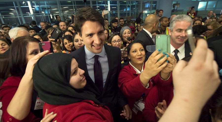 Canadian Prime Minister Justin Trudeau, centre, poses for a selfies with workers before he greets refugees from Syria at Pearson International airport, in Toronto, on Thursday, Dec. 10, 2015. (Nathan Denette/The Canadian Press via AP) The Associated Press