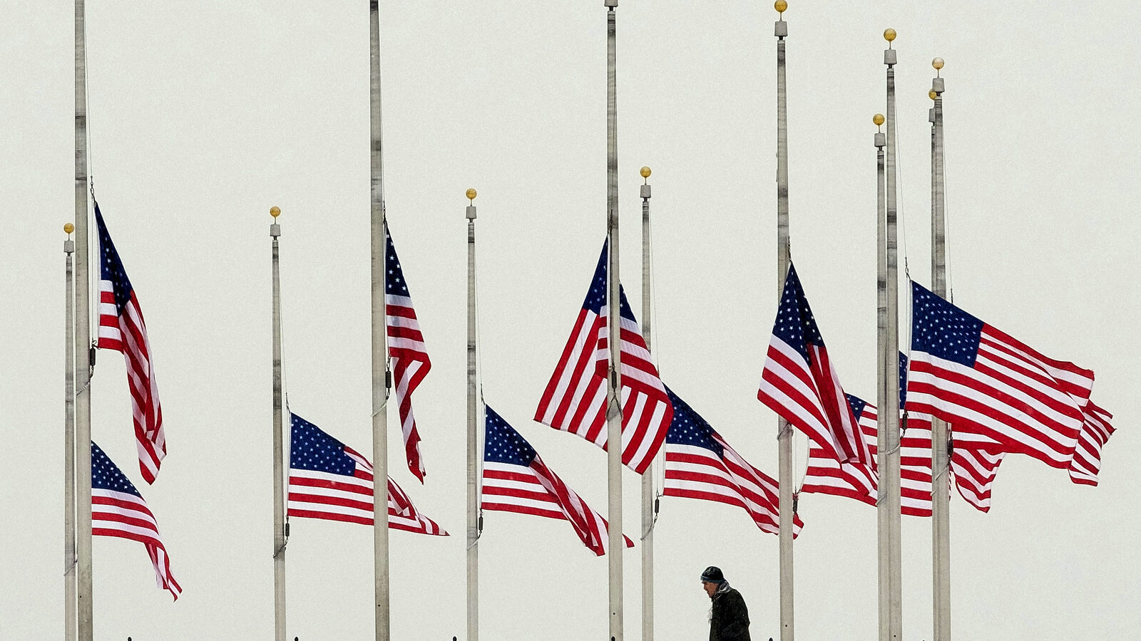 A vistor to the Washington Monument walks past flags flying a half-staff in honor of Supreme Court Justice Antonin Scalia on a wintry Presidents Day holiday in Washington, Monday, Feb, 15, 2016. (AP Photo/J. David Ake)