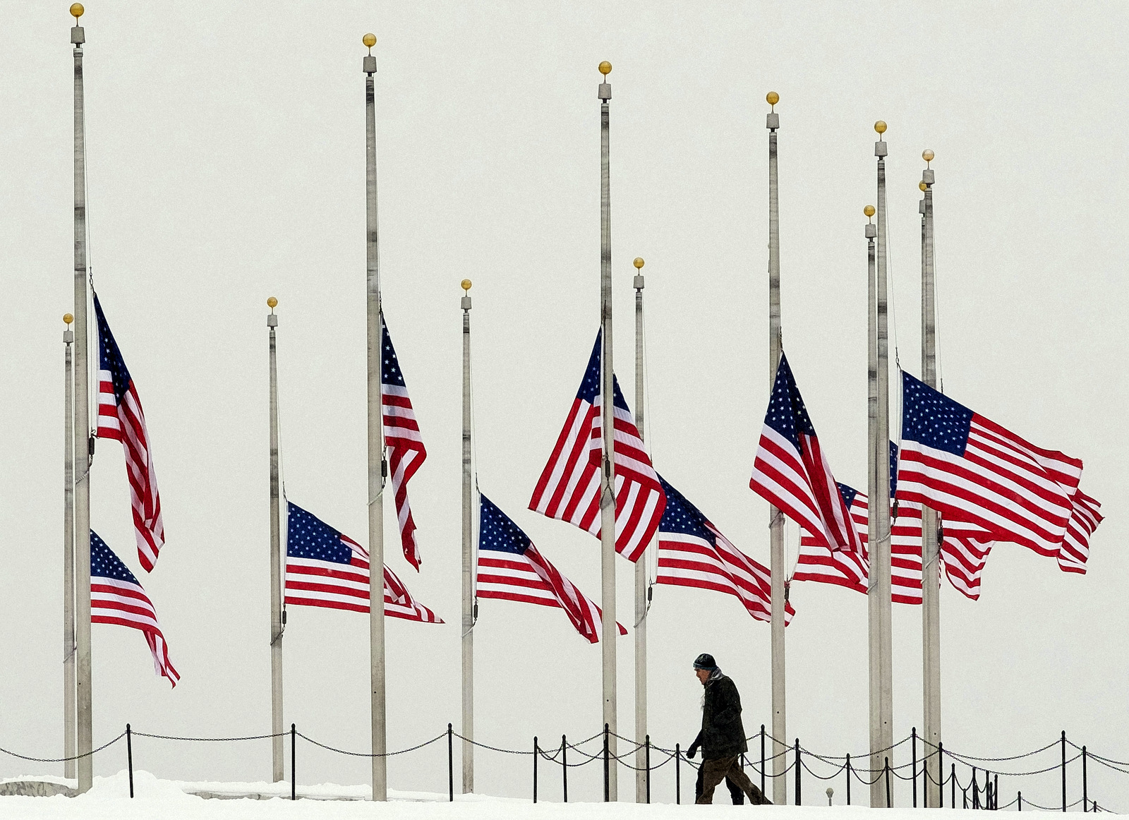 A vistor to the Washington Monument walks past flags flying a half-staff in honor of Supreme Court Justice Antonin Scalia on a wintry Presidents Day holiday in Washington, Monday, Feb, 15, 2016. (AP Photo/J. David Ake)