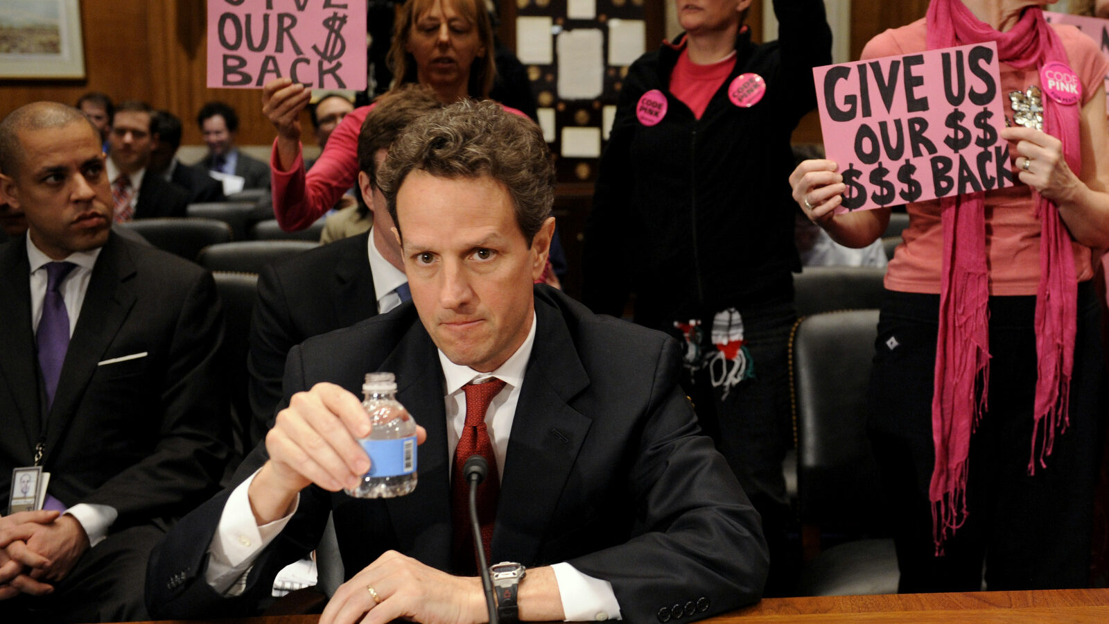 Members of CodePink stand behind Treasury Secretary Timothy Geithner on Capitol Hill in Washington, Tuesday, April 21, 2009, prior to his testifying before the Congressional Oversight Panel hearing on the Troubled Asset Relief Program (TARP).